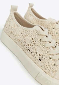 Beige Schnürer aus Spitze mit einem gehäkelten Obermaterial, runder Zehenpartie, strukturierten Mustern und flacher Gummisohle mit kontrastierendem Nähen.