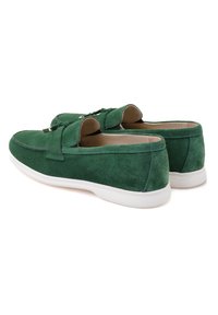 Green suede slip-on shoes with a rounded toe, white rubber sole, and minimalistic design featuring a decorative strap across the front.
