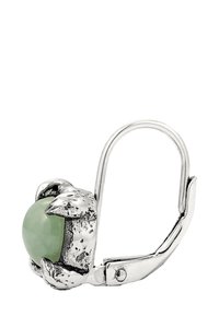 Ohrringe in Silberoptik mit einem grünen Stein, der von krallenartigen Akzenten gehalten wird. Die Ohrringe haben eine glatte, runde Form und eine detailliert strukturierte Oberfläche.