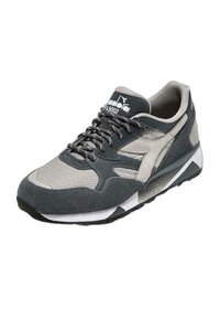 Scarpe sportive con tomaia in mesh grigia e nera, dettagli in camoscio, colletto imbottito, lacci piatti e suola in gomma texturizzata.