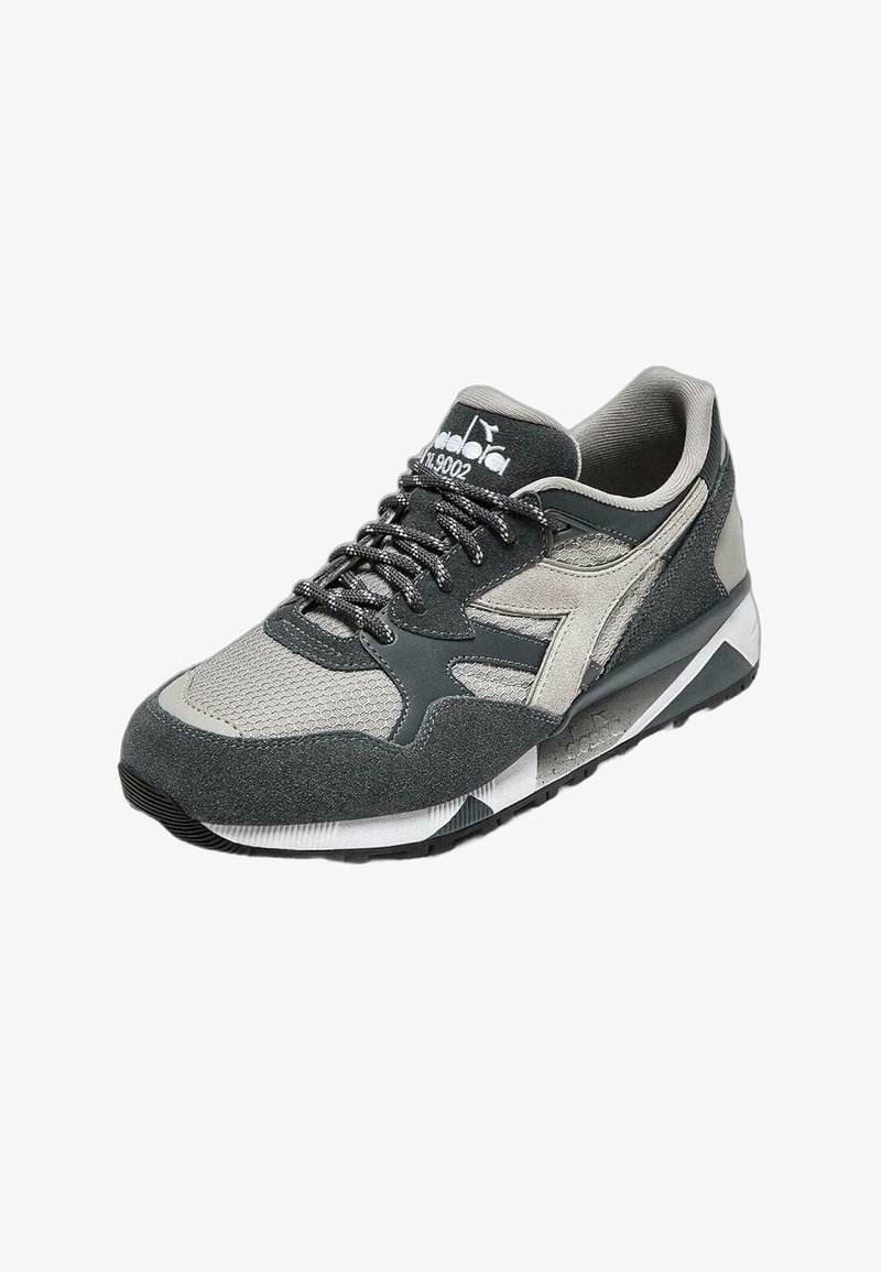 Scarpe sportive con tomaia in mesh grigia e nera, dettagli in camoscio, colletto imbottito, lacci piatti e suola in gomma texturizzata.