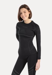 Czarna sportowa bluzka z długim rękawem wykonana z elastycznego materiału o dopasowanym kroju, z delikatnymi teksturowanymi wzorami i okrągłym dekoltem.