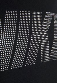 Lähedane vaade säravate rhinestone'idest, mis moodustavad julget kirjaviisi mustal kangal, luues särava tekstikujunduse.