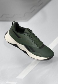 Scarpa sportiva verde con tomaia in mesh testurizzato, dettagli neri e una robusta suola intermedia bianca. Presenta un design con lacci e suola in gomma per una buona aderenza.