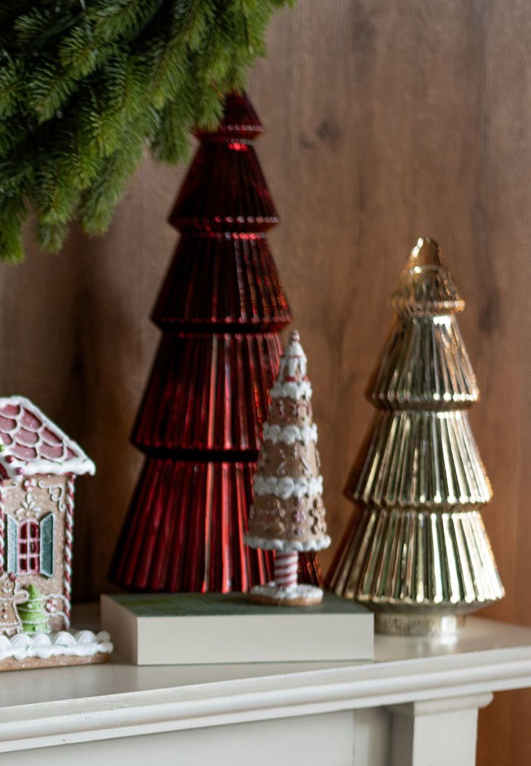Trois arbres de Noël décoratifs en verre de couleurs rouge, or et blanc, avec des textures à rainures verticales, exposés sur une étagère blanche.