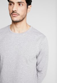 Gray long-sleeve T-shirt with a round neckline, made of soft cotton blend fabric. Features a smooth texture and relaxed fit.
