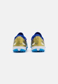 Scarpe da calcio blu e oro con una finitura lucida, dotate di un retro testurizzato, accenti bianchi e suole blu chiodate per una migliore aderenza.