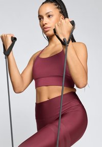 Μαρόν αθλητικό σουτιέν και κολάν ψηλόμεσα κατασκευασμένα από ελαστικό υλικό, με υφή στα κολάν. Κρατάει αντιστάθμισεις ασκήσεων.