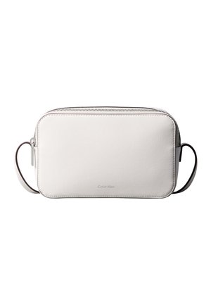 Bílá obdélníková kožená kabelka přes rameno se stříbrným zipem a tenkým nastavitelným popruhem, s jemným logem Calvin Klein na přední straně.