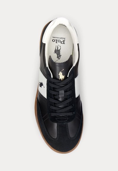Black and white sneakers with leather and suede materials, featuring a lace-up design, gum sole, and a logo printed inside.