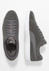 Sneaker in suede grigio con texture liscia, suole in gomma bianca e design con lacci, caratterizzati da un logo laterale e collo imbottito per il comfort.