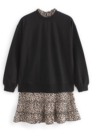 Czarna bluza z okrągłym dekoltem i długimi rękawami, nałożona na beżową, wielowarstwową sukienkę z czarnym wzorem w panterkę.