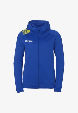 Haut zippé bleu en tissu doux, avec un motif géométrique jaune sur l'épaule, des poches avant et une capuche. Logo de la marque affiché.