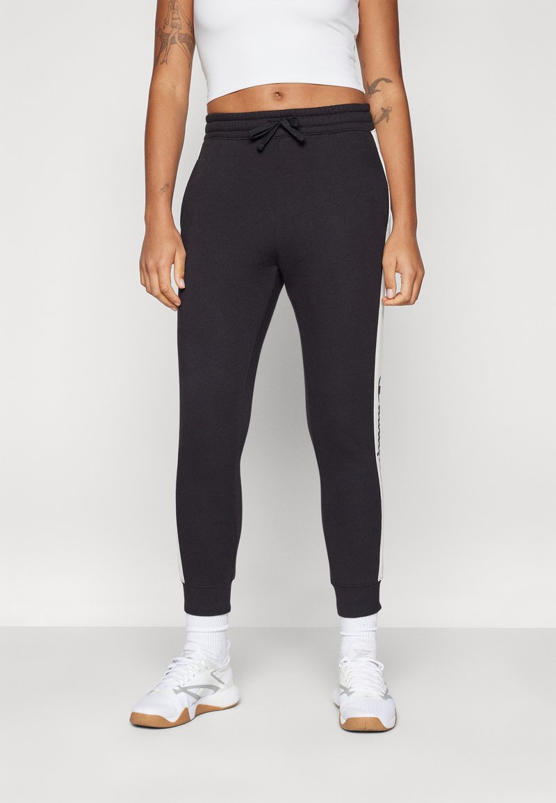 Sorte joggebukser med snor i taljen, slim fit og hvide sidelister. Lavet af blødt stof, med tætsiddende manchetter og lommer.
