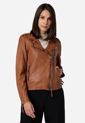Giacca da biker in pelle marrone con design cropped, zip asimmetrica e accessori in argento. Presenta tasche con cerniera e dettagli sulle maniche.