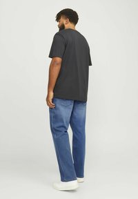 T-shirt nera a maniche corte e jeans azzurri chiari. La t-shirt ha una vestibilità comoda, con scollatura rotonda e design semplice. Sneakers bianche completano il look.