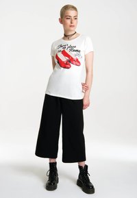 White T-shirt featuring red, sparkly shoes graphic with "There's no place like Home" text. Paired with black culottes and lace-up boots.