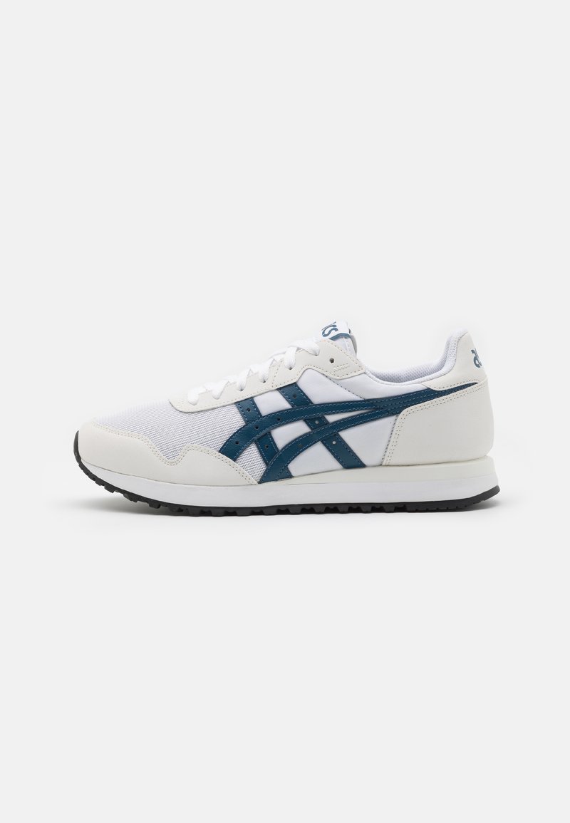 White athletic shoe with a mesh upper, dark blue accents, and black rubber sole. Features a lace-up design and cushioned collar.