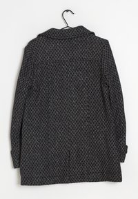 Abrigo de patrón de espiga en negro y gris, con mangas largas, un cuello y un lazo colgante, hecho de tela texturizada.