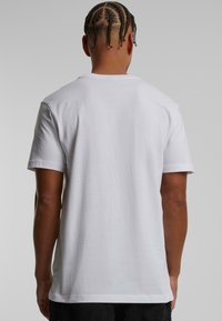 Hvid bomulds t-shirt med rund hals og korte ærmer, der har en glat tekstur og en afslappet pasform, vist fra ryggen.