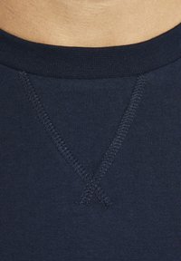 Dunkelblauses Baumwollhemd mit Rundhalsausschnitt, ausgestattet mit gerippten Abschlüssen und einem V-Stich-Detail am Kragen. Weiche Textur und glatte Oberfläche.