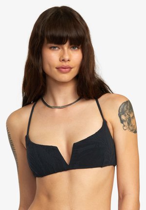 Haut de bikini noir avec un design en V, en tissu texturé, avec des bretelles fines et une forme structurée. Présente des motifs géométriques et un style minimaliste.