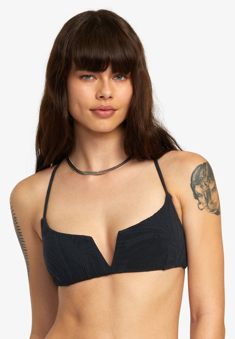 Zwarte bikinitop met een V-halsontwerp, textuurstof, dunne bandjes en een gestructureerde vorm. Bevat geometrische patronen en heeft een minimalistische stijl.