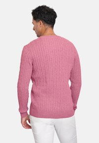 Jersey de punto rosa con canalé, de manga larga y escote redondo. Presenta una textura horizontal y un dobladillo ajustado. Adecuado para un look casual.