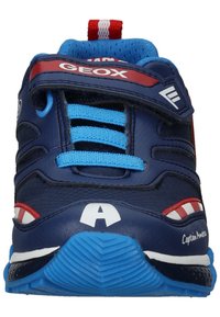 Blaue Sportschuhe mit roten Akzenten, ausgestattet mit einem strukturierten Obermaterial, einem Klettverschluss und einer kontrastierenden Gummisohle mit Wellenmuster.