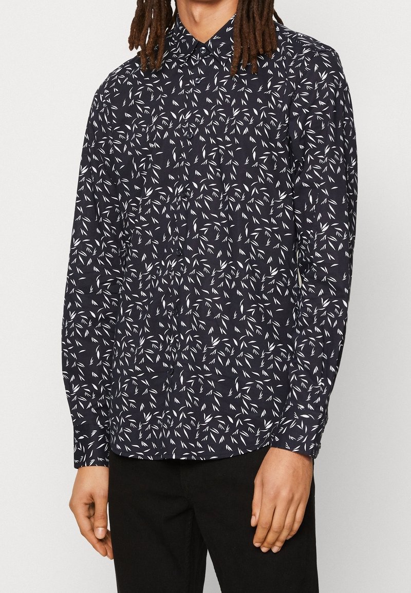 Laivaston napillinen paita, jossa on valkoisia lehtikuviota, pitkät hihat ja kaulus. Valmistettu kevyestä kankaasta, jossa on normaali istuvuus ja hihansuut.