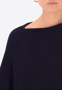 Maglione in blu navy, lavorato a maglia, con scollo ampio e tessuto texture. Presenta un design con spalla abbassata per una vestibilità rilassata.
