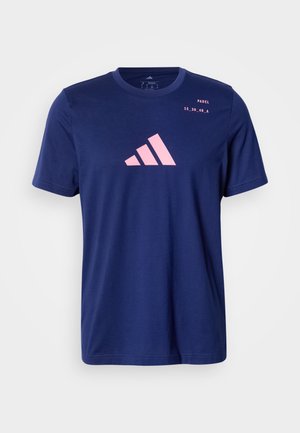 Camiseta de algodón azul marino con mangas cortas que presenta un logo de Adidas en rosa y textos impresos en el frente. Cuello redondo, corte estándar.