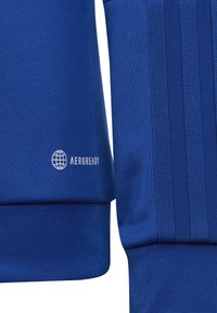 Felpa sportiva blu caratterizzata da un tessuto testurizzato, orlo a costine e tre strisce sulle maniche. Include un piccolo logo bianco "AEROREADY".