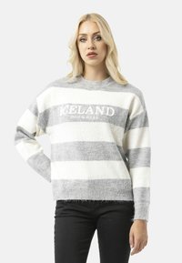 Pull rayé gris clair et blanc avec un col rond. "ISLANDE" est brodé sur le devant. Matériau doux et texturé, avec une coupe décontractée.