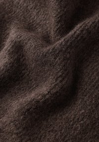Brązowy, teksturowany materiał o miękkim, puszystym wyglądzie, z wzorem dzianiny i lekko nierówną powierzchnią, które sugerują ciepło i komfort.