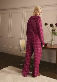 Sarkana un rozā četrinieku krekliņa komplekts ar pogājamu krekliņu un platu kāju biksēm. Mīksts audums, brīvs piegriezums un minimālistiskas dizaina detaļas.