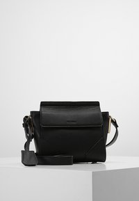 Black leather crossbody bag with a structured shape, top flap closure, textured surface, and gold-tone hardware accents.