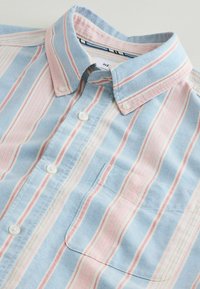 Nööbitav triiksärk siniste, roosade ja valgete vertikaalsete triipudega, esitaskuga ja helesinise kraega, millel on nööbkinnitused.