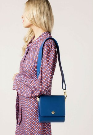 Niebieska skórzana torebka crossbody o prostokątnym kształcie, z akcentami w złotym kolorze i zapięciem na klapę. Torebka ma teksturowane wykończenie.