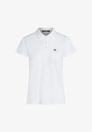 Λευκό κοντομάνικο πόλο πουκάμισο με γιακά και τρία κουμπιά, με μικρό λογότυπο ενός προσώπου με γυαλιά ηλίου στο αριστερό στήθος.