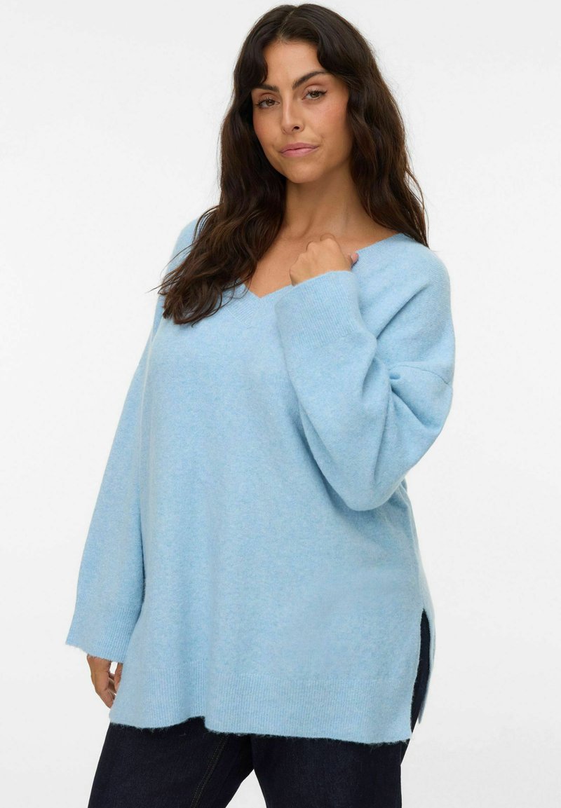 Lichtblauwe oversized trui met een V-hals, lange mouwen en zijsplitten. Zachte textuur met een relaxte pasvorm, gemaakt van een comfortabele gebreide stof.