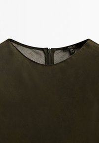 Dark green blouse featuring a round neckline, concealed zipper at the back, and a smooth textured fabric. Tag visible inside collar.
