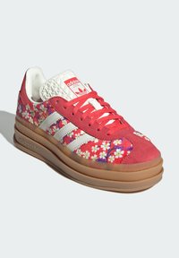 Rote Wildleder-Sneaker mit floralem Stickmuster, weißen Lederakzenten und drei weißen Streifen. Enthält eine gemusterte Mesh-Zunge und eine Gummisohle.