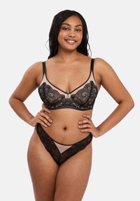 Ensemble de lingerie en dentelle noire avec un design transparent, des bords festonnés et des bretelles ajustables, accompagné d'un string assorti et de détails élaborés.