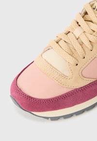 Sneaker med en blanding av beige suede og rosa tekstil, med en teksturert tåhette og snørebånd, supplert med en grå gummisåle.