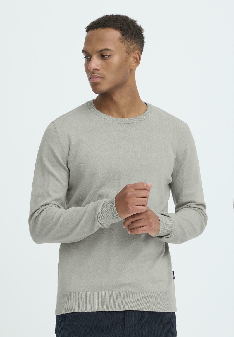 Helles grauer Pullover aus weichem Strickmaterial, mit klassischem Rundhals, langen Ärmeln und gerippten Bündchen und Saum. Minimalistisches Design.