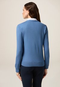 Hellblauer Cardigan aus hochwertigem Strickmaterial. Hat einen V-Ausschnitt, lange Ärmel und gerippte Bündchen und Saum. Einfaches und sauberes Design.