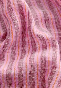 Tissu textile avec des rayures verticales alternées en rose, bordeaux et orange, montrant un tissage texturé et des plis doux.