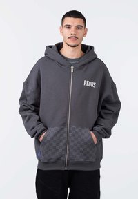 Felpa grigia con zip, realizzata in tessuto morbido, con un ampio cappuccio, tasche frontali con inserti decorati e un logo sul petto.