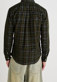 Dunkelgrünes Kariertes Hemd mit langen Ärmeln, Manschetten mit Knöpfen und Rückenpasse. Das Muster umfasst Linien in Rost, Blau und Gelb.